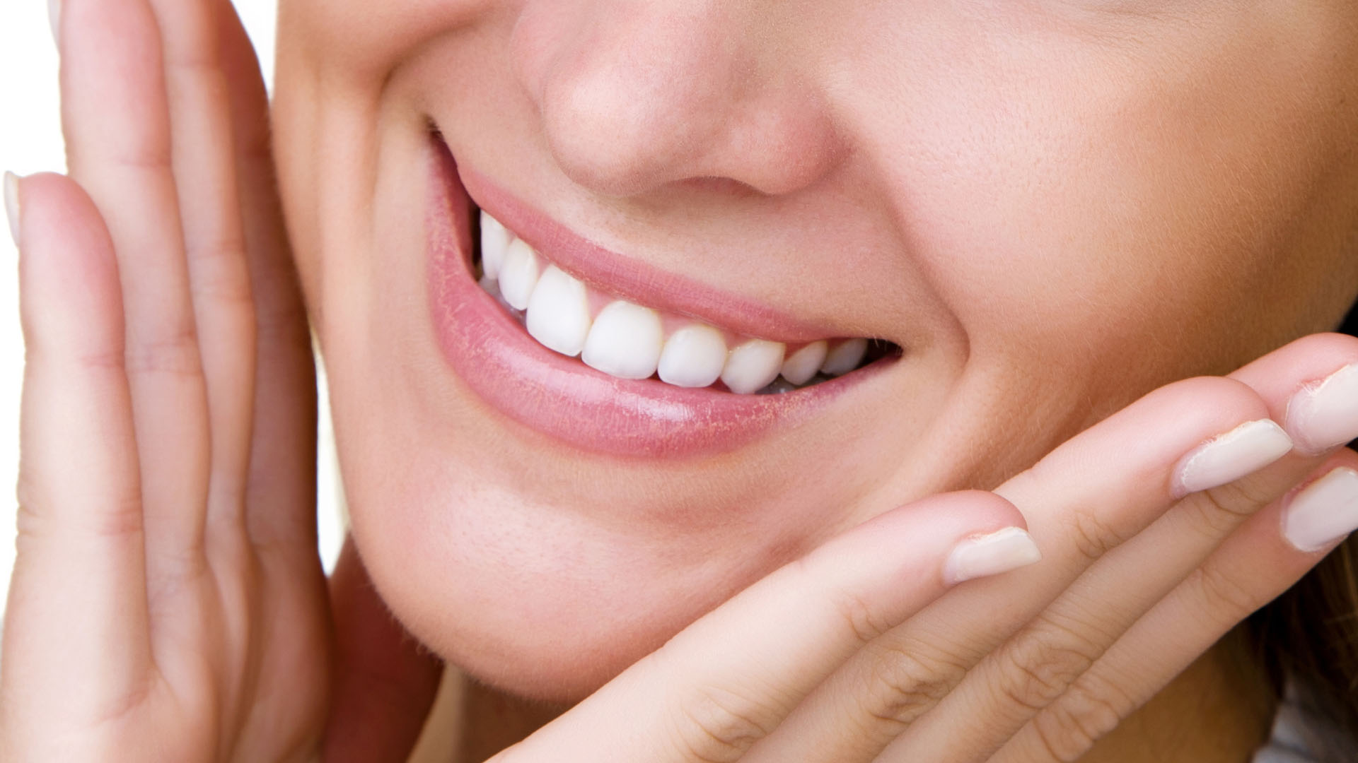 Close-up of a woman smiling with bright white teeth, both hands gently framing her face